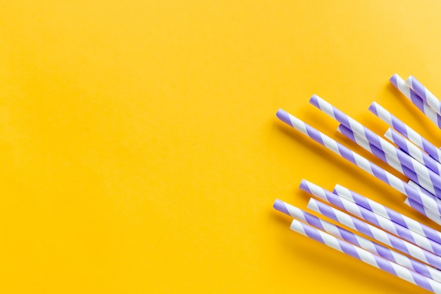 Drinking straws for party on yellow background. Top view of colorful paper, eco-friendly straws for summer cocktails. Drinking paper colorful straws for summer drinks.Copy space