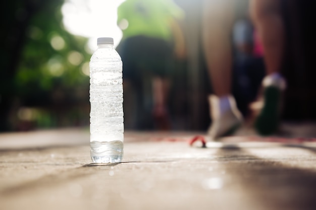 Drinking water bottle on ground and blurred people exercise by jogging 