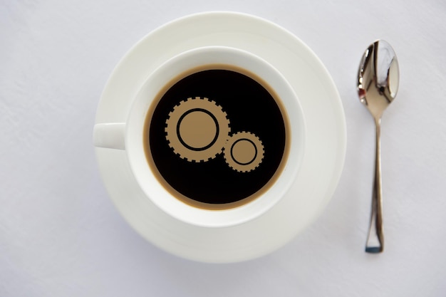 drinks, energetic, efficiency and caffeine concept - cup of black coffee with cogwheel symbol on surface and spoon