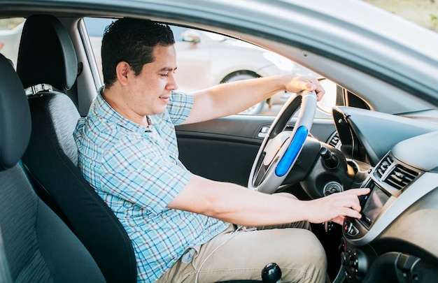 Driver man changing the radio station Smiling driver tuning into the radio station Distracted driver concept tuning the radio Driving people changing radio station