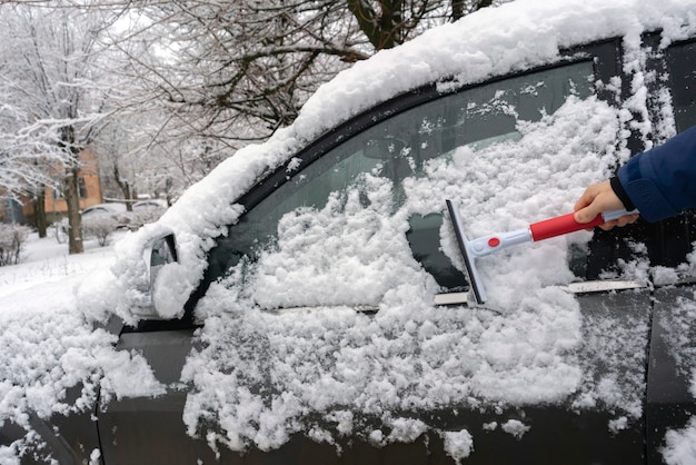 The driver's hand creaning the car from snow in the morning before the journey