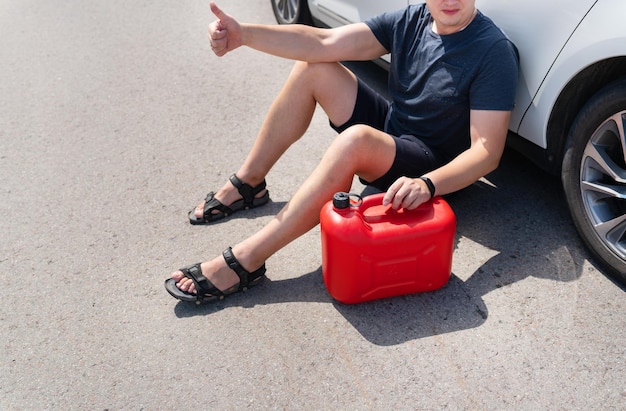 The driver wants to refuel in an empty car tank an empty red canister on the side of the road Stops on the road Fuel problem force majeure