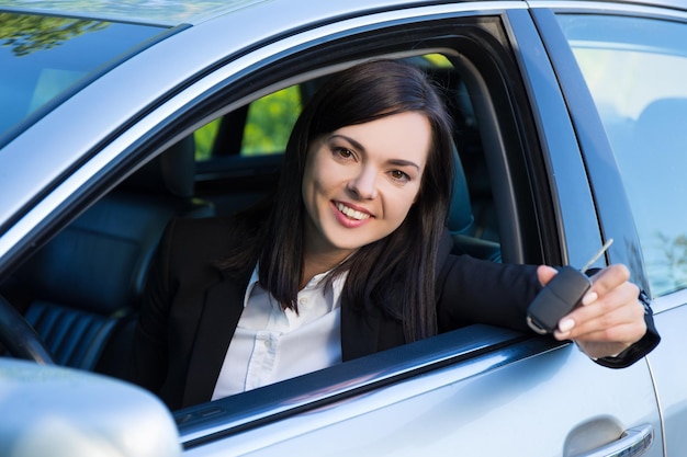 driving concept -happy smiling young woman with car key