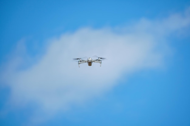 A drone is flying in the sky with a white box on the front.