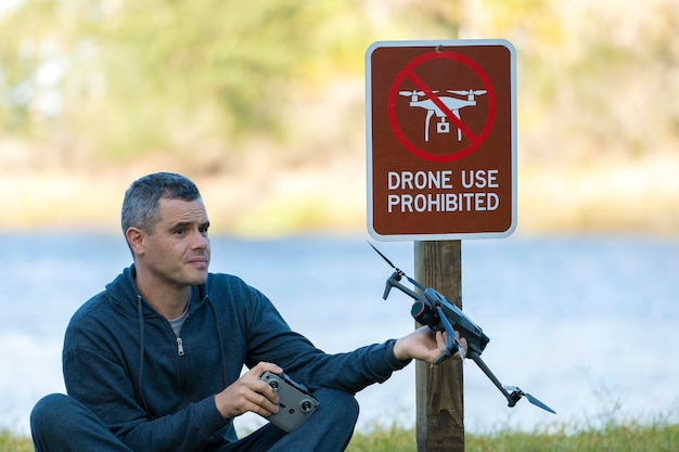 Photo drone operator is disappointed because he isn't allowed to fly his quadcopter in national park no drone area man is unable to use his uav near restriction notice sign airspace use regulations