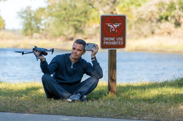 Photo drone operator is disappointed because he isn't allowed to fly his quadcopter in national park no drone area man is unable to use his uav near restriction notice sign airspace use regulations