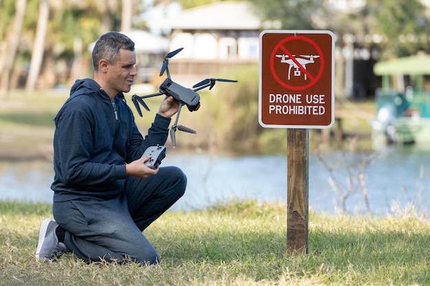 Drone operator is disappointed because he isn't allowed to fly his quadcopter in national park no drone area Man is unable to use his UAV near restriction notice sign Airspace use regulations