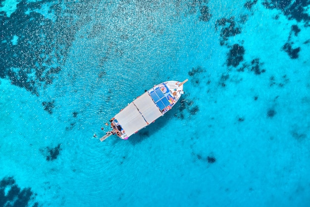 Drone photo top view of boat in turquoise sea bay