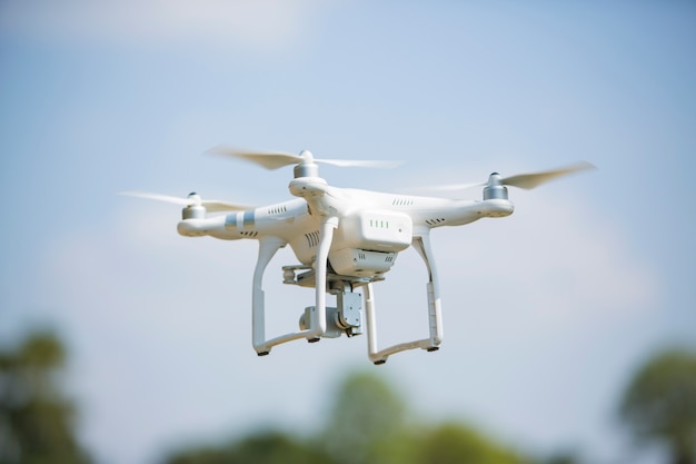 drone quad copter with high resolution digital camera flying hovering in the blue sky 