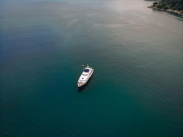 Drone shot of the beautiful white yacht in the warm blue sea; millionaire concept.