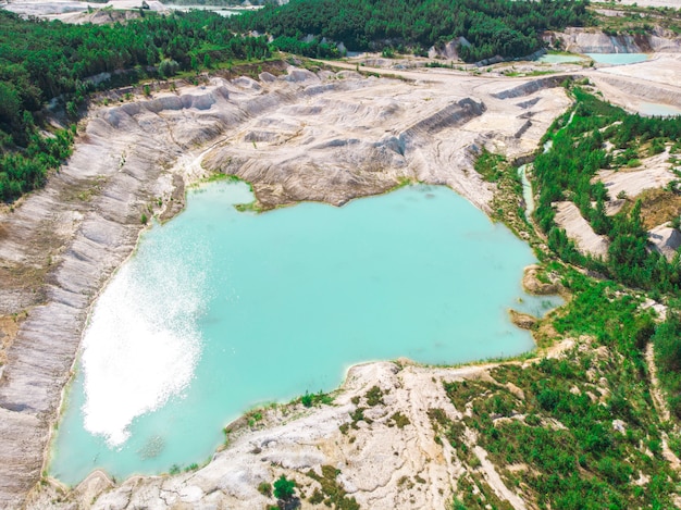 Drone view on a flooded kaolin quarry with turquoise water and white shore