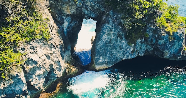 Drone view ocean with waves hitting the rocks on the seashore