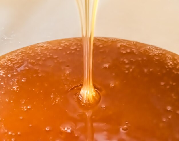 Photo drop of bee honey drip from hexagonal honeycombs