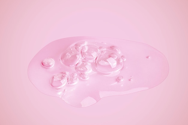 A drop of transparent gel smeared on a pink background