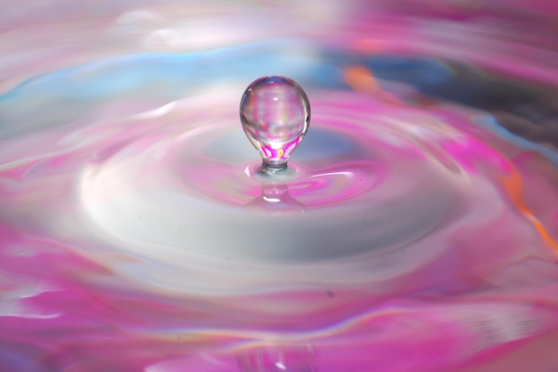 Photo a drop of water falls into colorful water