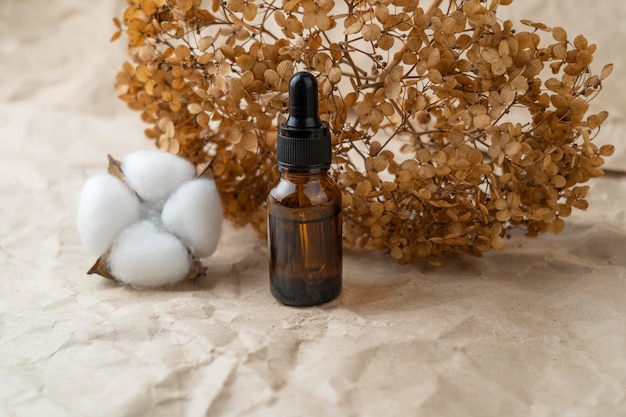 A dropper bottle with face serum or natural oil standing on a craft paper background