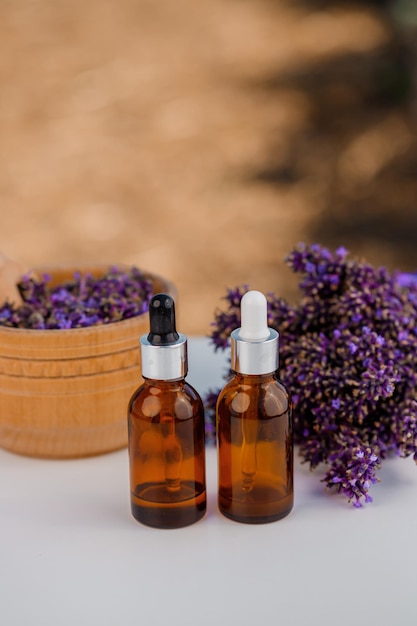 Dropper bottle with lavender cosmetic oil or hydrolate against lavender flowers field as background with copy space Herbal cosmetics and modern apothecary concept