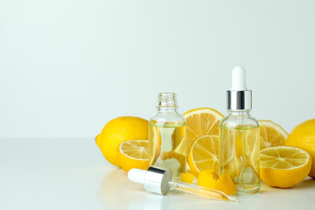 Dropper bottles with oil and lemons on white table