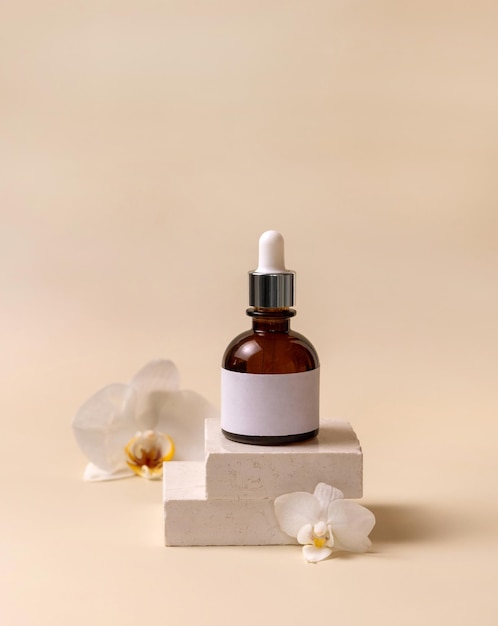 Dropper glass bottle on stone near white orchid flowers on light yellow Cosmetic Mockup