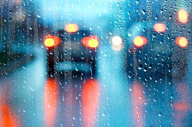 drops on glass auto road rain autumn night / abstract autumn background in the city, auto traffic, romantic trip by car