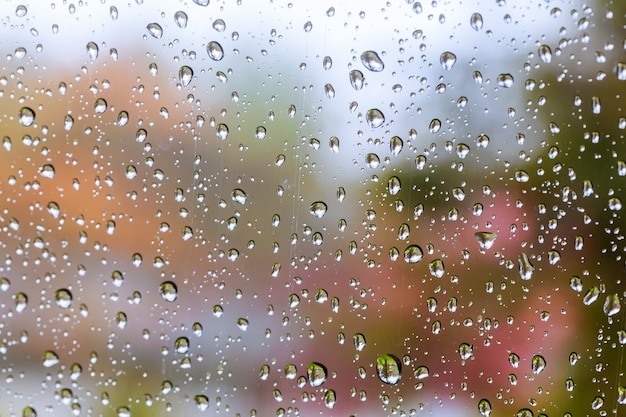 Drops Of Rain On Blue Glass Background. Street Bokeh Lights Out Of Focus.