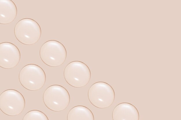 Drops of transparent gel or water in rows On a beige background