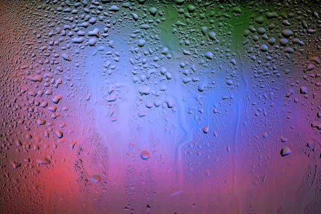 Photo drops of water on the glass drops of rain on the window abstract background colorful spots