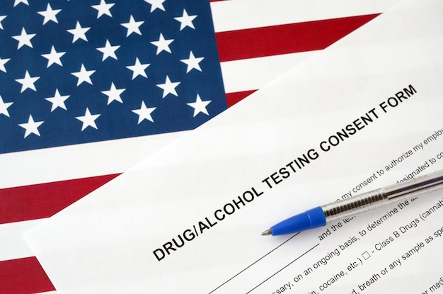 Drug and alcohol testing consent form with blue pen on United States flag