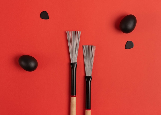 Drum brushes shakers and guitar picks on a bright red background Top view flat lay