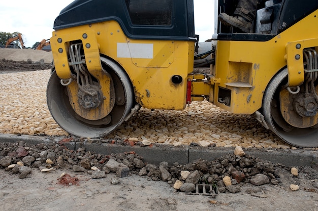 Drum Ride On Roller compacting freshly laid tarmac during roadworks and new footpath construction