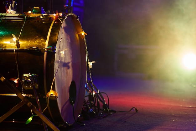 Drum set on stage bass drum close-up in fog and multi-colored lighting