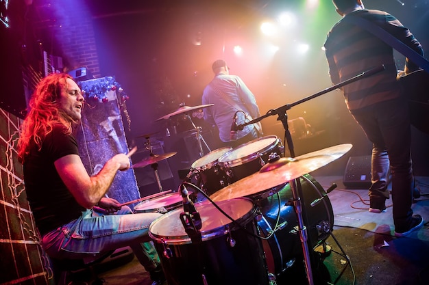 Drummer playing on drum set on stage. Authentic shooting with high iso in challenging lighting conditions. A little bit grain and blurred motion effects.