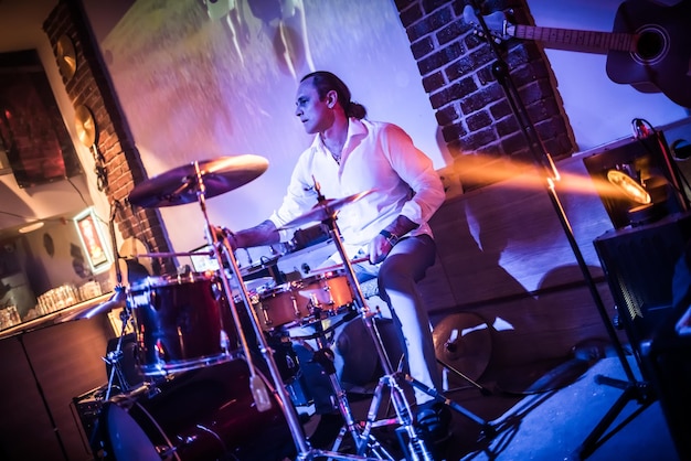 Drummer playing on drum set on stage. Warning - authentic shooting with high iso in challenging lighting conditions. A little bit grain and blurred motion effects.