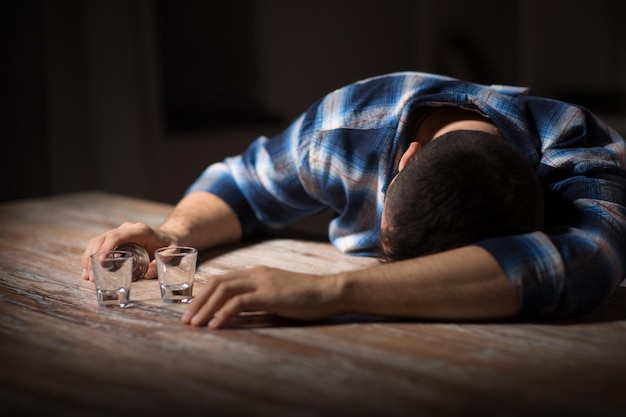 drunk man with empty glasses on table at night