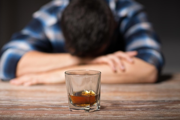 drunk man with glass of alcohol on table at night