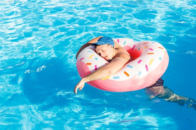 Drunk resting guy on the inflatable circle in the swimming pool of the hotel