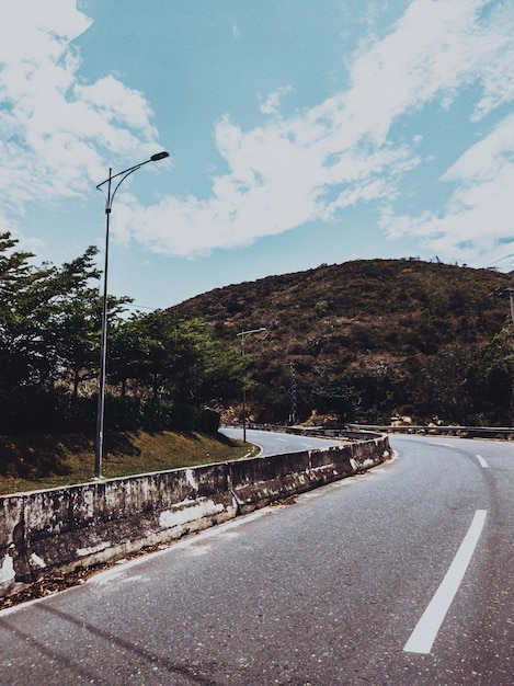 Dry asphalt empty automobile road with concrete barrier and marking lines on a sunny summer day with blue cloudy sky Car travel trip concept background Stories vertical format Dark green style