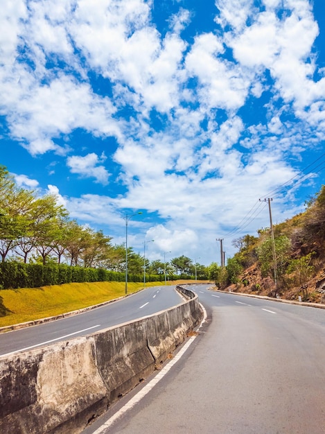 Dry asphalt empty automobile road with concrete barrier and marking lines on a sunny summer day with blue cloudy sky Car travel trip concept background Stories vertical format