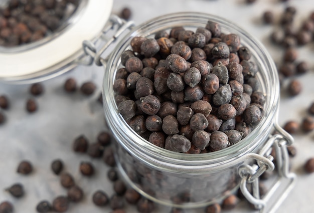 Dry black chickpea from Apulia and Basilicata in Italy in the glass jar on grey marble table with copy space, closeup