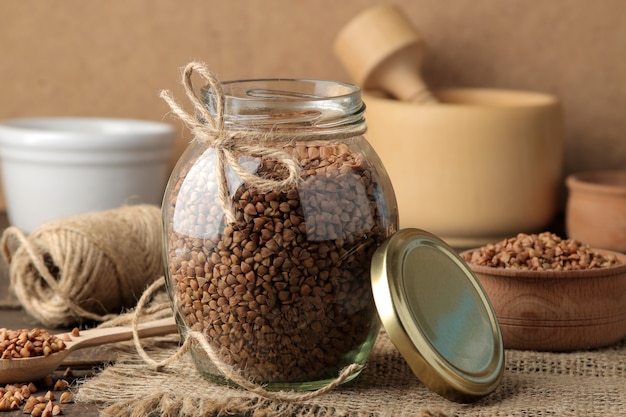 Dry buckwheat groats in a glass jar in the foreground on a wooden brown table. cereals. healthy food. porridge.