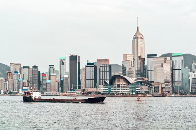 Photo dry cargo vessel and victoria harbor in hong kong at sunset. view from kowloon on hk island.