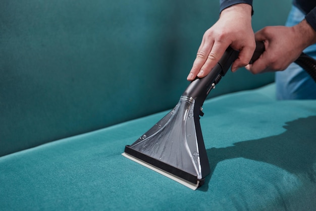 Dry cleaning worker removing dirt from sofa indoors