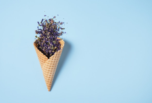 Dry cornflower tea falls out of a waffle cone