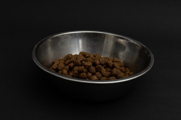 Dry dog food in an aluminum plate on a black background dog food