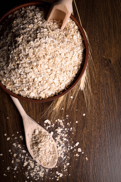 Dry flakes in a wooden bowl on a wooden table near the ears of wheat. wooden spoon with Dry flakes