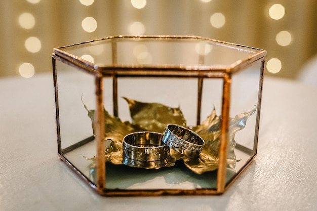 Dry golden leaves with wedding rings in a metal box Luxury elegant Wedding decor for the ceremony Autumn style Engagement