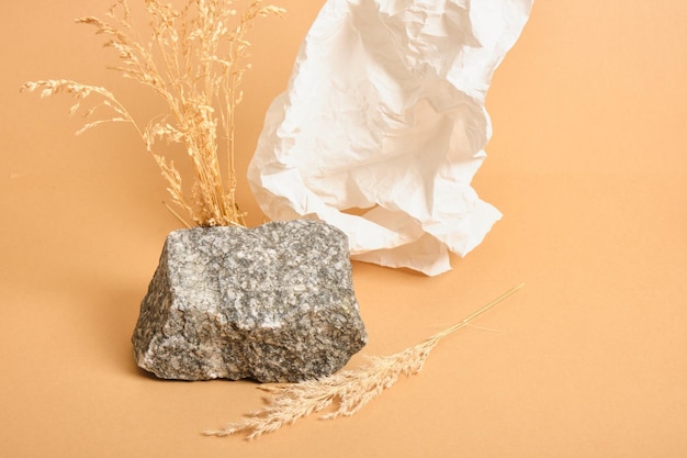 Dry grass, crumpled white paper and natural stone on a beige background, background for the presentation of your organic product mock up copy space