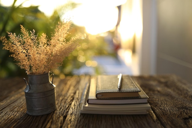 Dry grass flower in stainless vase and notebooks