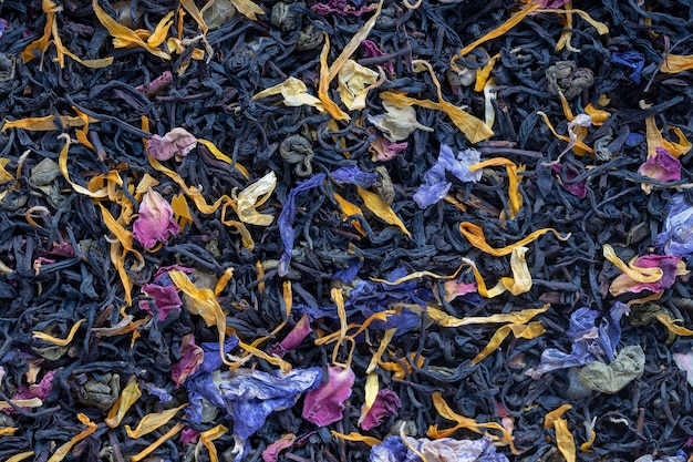 Dry herbs tea with fruit and flower petals as background, top view. Healthy eating concept