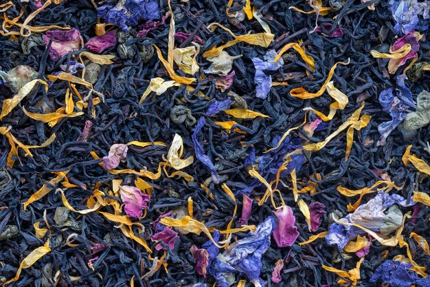 Dry herbs tea with fruit and flower petals as background top view